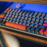 Ergonomic Accessories - From above contemporary mechanical keyboard of black and red colors with lightning placed on wooden computer desk