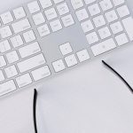 Peripherals - Wireless Keyboard and Airpods Case Next to Glasses